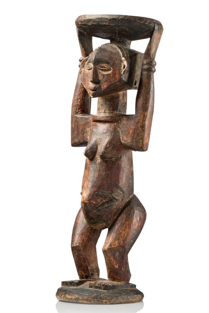 Female caryatid stool - D. R. Congo, Luba. 
wood, pigments, old collection label, inscribed: "1.C.32736. Central Afrika. Congo. Manjema. Holz-Figur. Gesch. Leutnant v. Parish", on reverse: "Orig. N:113."; handwritten number in two places: "32736" and "...3273..."
The caryatid stool is the characteristic emblem of Luba rule, and served as a dwelling place for the king's spirit. 